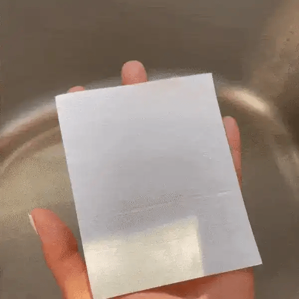 Feuille de lessive GREEN DETER tenue à la main près de l'eau